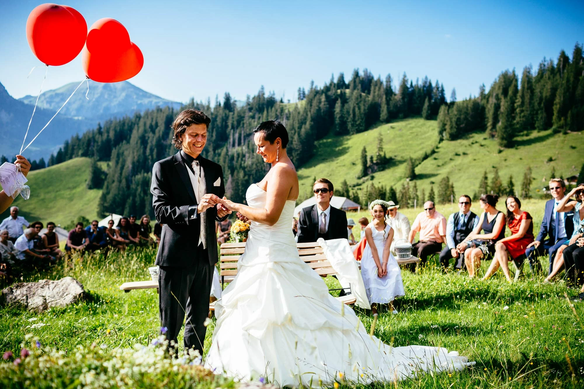 Brautpaar steckt Ehering an auf einer Alpwiese