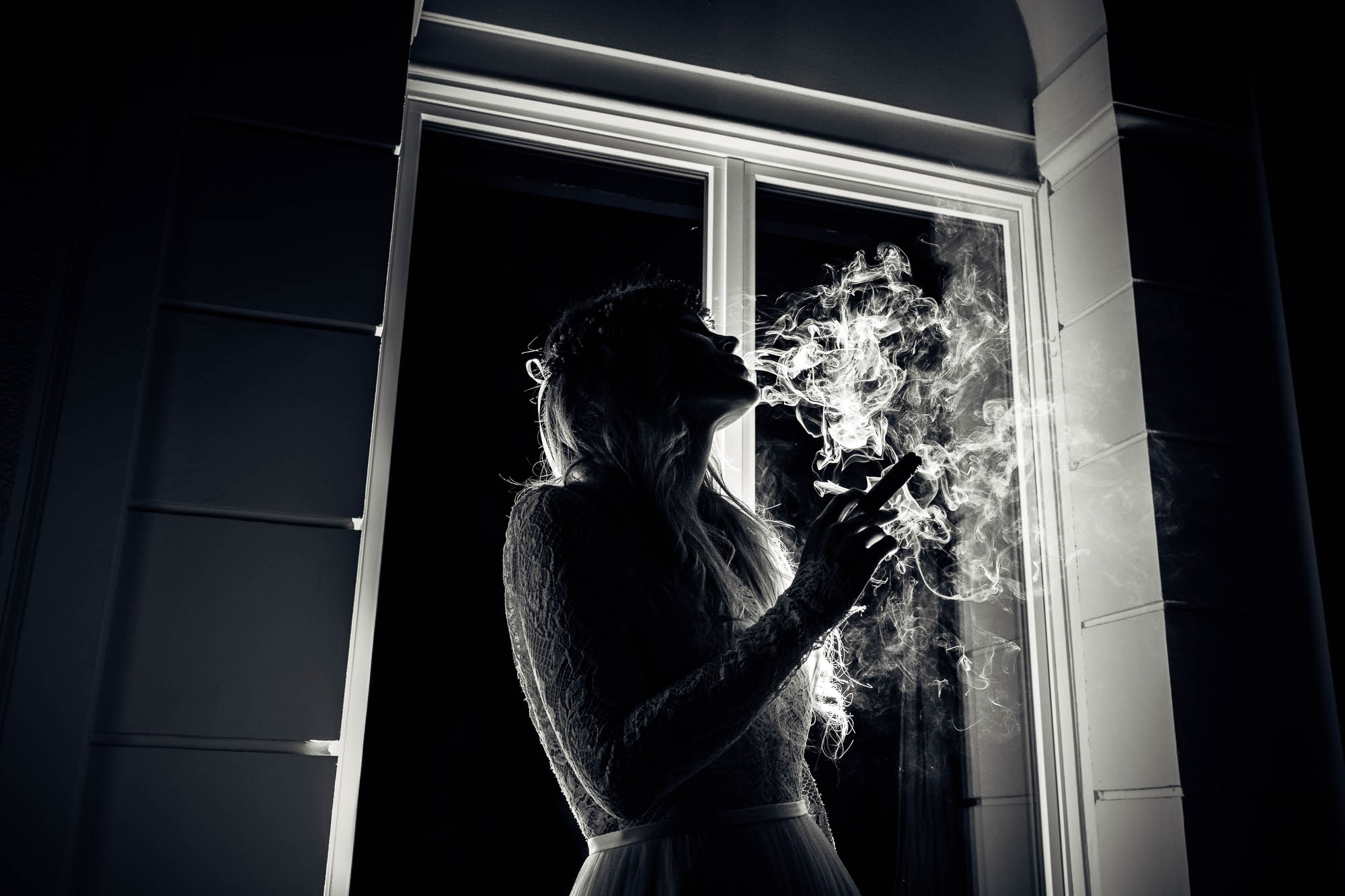Braut raucht einen Stumpen mit viel Rauch im Gegenlicht
