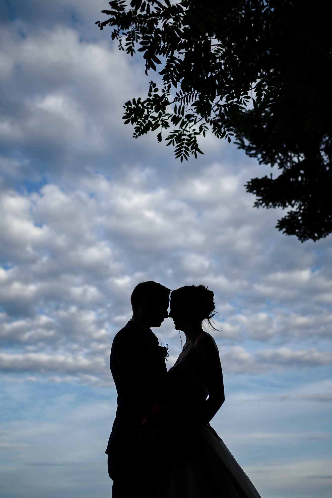 Brautpaar Silhoutte vor blauem Himmel mit Wolken